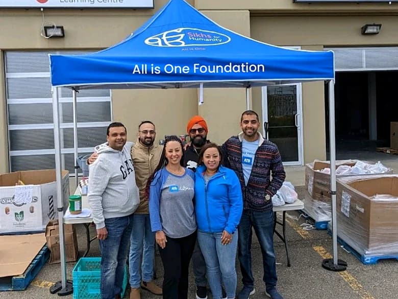 The volunteer team standing together under the All is One Foundation tent