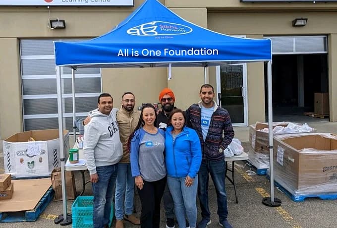 The All is One volunteer team standing together under the foundation's tent