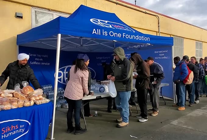 Volunteers serving food and water to a line of people at the foundation's tent